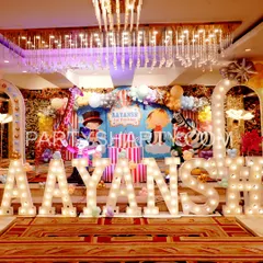 A grand stage for a carnival party, featuring large marquee letters, circus animal props, and a backdrop with a ringmaster and zebra.