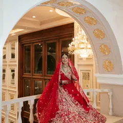 A full-length view of this magnificent bridal look. The grand setting and her stunning red lehenga called for makeup that was both classic and striking, ensuring she was the center of attention.