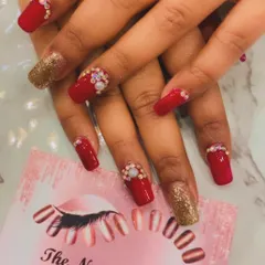 A classic party look with bold red square nails and gold glitter accent nails. The red nails are further embellished with clusters of opulent crystals at the cuticle for a rich, festive feel.