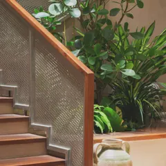 A detailed look at the staircase railing. The design combines a warm wood handrail with a perforated metal screen, a modern detail that allows light to filter through while ensuring safety.