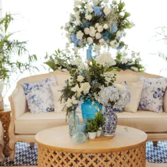 A cozy lounge nook from the blue and white engagement. The classic sofa is adorned with Chinoiserie-print cushions, and the carved wooden coffee table holds an assortment of blue and white vases, blending textures and patterns beautifully.