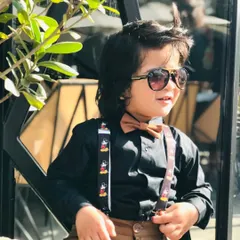 The same dapper young model, adding a pair of sunglasses to his look. Styling for kids is about creating outfits that are both fashionable and fun.