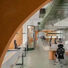 A view through the terracotta-textured arches of the Hosachiguru office. The open layout was designed to eliminate hierarchical barriers and encourage communication, with a minimal design that reflects the company's focus on sustainability.