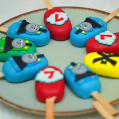 A closer look at the Thomas & Friends themed cakesicles we made for Damian's birthday party. These bite-sized treats are perfect for party favors and are customized to match the main cake, featuring Thomas's face and the birthday number.