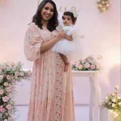 A mother holds her daughter, both dressed beautifully for the party. These are the precious moments that make every event special.