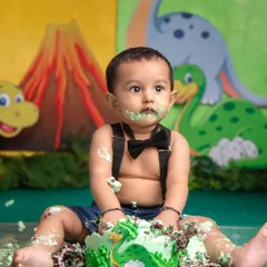 This little dino fan is having a messy but delicious time with his prehistoric-themed cake. The look of pure satisfaction says it all.