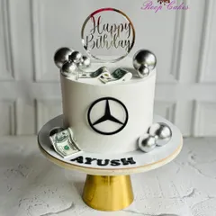 A classy cake for a classy celebration. This Mercedes-themed birthday cake features the iconic logo, edible dollar bills, and silver spheres for a touch of luxury.