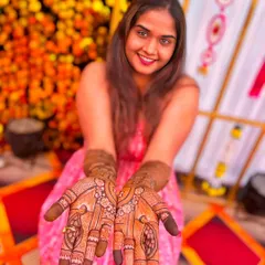 A happy bride showing off her beautiful wedding mehndi. The design features classic peacock motifs and delicate floral patterns, with a guaranteed dark stain from our natural henna.