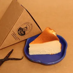 A perfect slice of my Basque Burnt Cheesecake, ready to be enjoyed. It's thick, creamy, and has that signature caramelized flavor, all without any sugar. It comes in its own convenient single-slice box.