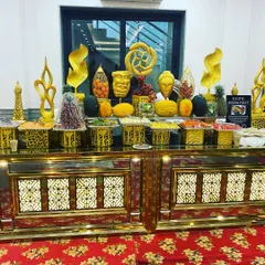 An exotic fresh fruit station set up for a luncheon. The counter features elaborate golden sculptures and a wide variety of local and imported fruits, creating a healthy and visually appealing option for guests.