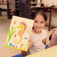 A smiling student shows off her beautiful seahorse painting. In this project, our 6 to 9-year-olds learned about the underwater world using watercolors.