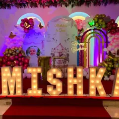 A butterfly-themed first birthday on a stage. This elaborate setup features large marquee letters, a carousel-themed backdrop, and multiple balloon arrangements.