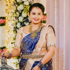 A happy client at a wedding, wearing a royal blue Kanjeevaram saree with a simple yet elegant beige embroidered blouse.