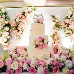 A wedding cake should be as magical as the love story it celebrates. This three-tiered buttercream cake, adorned with fresh pink and white roses and a custom "Mr & Mrs" topper, was the centerpiece of a beautiful floral-themed reception.