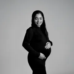 A classic black and white portrait of a mom-to-be cradling her bump. The simple composition and lighting create an elegant and timeless feel.