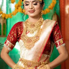 This is my classic South Indian temple jewellery set, featuring intricate gold work with goddess motifs. The set includes a choker, a long haram necklace, jhumkas, a maang tikka, and a kamarbandh, perfect for a traditional bridal look.