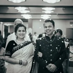 A timeless black and white photograph from an engagement ceremony. The couple makes their entrance, showered with petals by their loved ones, creating a classic and celebratory image.