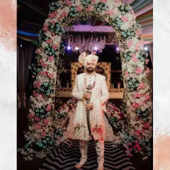 A groom stands proudly under a floral arch in our intricately embroidered off-white sherwani. This outfit is perfect for a grand entrance, complete with a matching safa and kirpan.