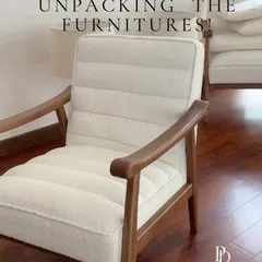 Unpacking new furniture is always an exciting moment in the design process. This plush, off-white armchair with a wooden frame is one of the key pieces selected for a luxurious and comfortable living area.