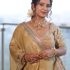 A full view of a timeless bridal look in golden hues. This showcases not just the makeup, but also the complete styling with hair and lehenga draping to create an elegant and cohesive appearance.
