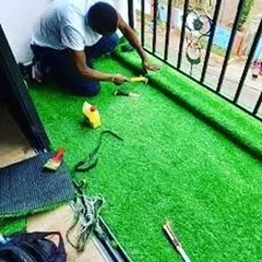 An installer from my team carefully cutting and fitting the turf along the railing of a balcony. I use proper tools to ensure the edges are neat and the entire installation is secure.