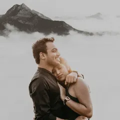Above a sea of clouds on a misty mountain, this couple's embrace feels like the only thing in the world. This black and white portrait focuses purely on the serene, powerful emotion of their bond during their outdoor couple photoshoot.