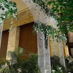 A detail of the entrance archway, where modern white lattice is adorned with cascading green and white wisteria. This creates a feeling of walking through a magical, contemporary garden.