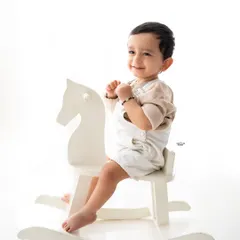A classic and simple portrait of a little boy on a white rocking horse against a clean white background. Timeless and sweet.