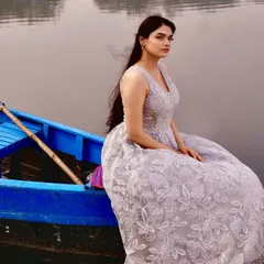 The wind catching the model's hair as she sits by the water perfectly captures the dreamy, romantic mood this lace gown evokes.