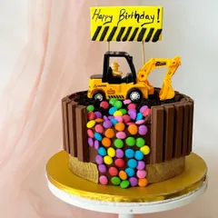 A fun KitKat-wrapped construction cake. The excavator on top is digging into the cake, revealing a surprise cascade of colourful gems.