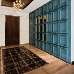 A full view of the blue coffered panel wall in the entryway. This element serves as both a powerful design statement and a clever way to integrate shoe storage seamlessly into the foyer.
