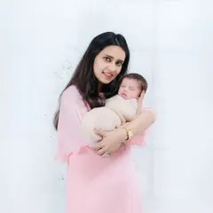 A beautiful portrait of a new mother in a soft pink dress holding her peacefully sleeping newborn. A memory of those quiet, early days.