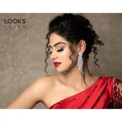 A side profile showcasing the elegant updo and shimmering eyeshadow of this party look. The subtle glow on the cheekbones and the classic red lip complete this sophisticated style.