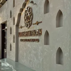 The entrance to the Koteshwaram restaurant features a textured concrete wall with traditional arched niches. The custom brass signage and emblem add a touch of heritage and elegance, setting the tone for the culturally-rooted dining experience inside.