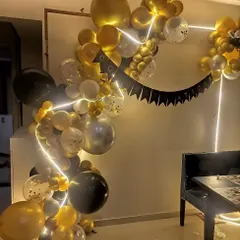 A free-flowing balloon garland in black, gold, and white. This modern arrangement is accented with a flexible neon tube light for a cool, glowing effect.