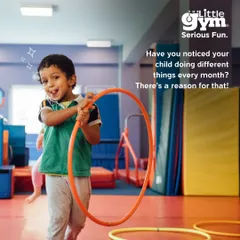 A preschooler enjoys a moment of fun with a hula hoop. Our monthly themes introduce new skills and challenges, keeping children engaged while they master body control and coordination.