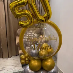 Celebrating the big 5-0! This custom standing balloon bouquet features giant gold '50' foil balloons and a personalized bubble balloon wishing Mom a happy birthday in a luxe gold and silver theme.