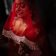A bride in her red veil, captured with soft, natural light. This intimate portrait focuses on the delicate details of her attire and her serene expression.