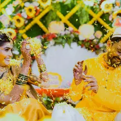 Pure, unadulterated fun at the Haldi! This candid shot captures the couple playfully throwing flower petals at each other, their faces lit up with laughter. These are the moments that truly define the celebration.