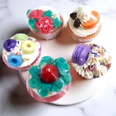 These are my cupcake soaps, and they are almost too cute to use. Each one is handcrafted with a piped frosting top and unique decorations like tiny macarons, roses, or coffee beans, making them a delightful and whimsical treat for your skin.