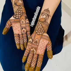 This design features a beautiful peacock perched inside a jharokha (window), a classic element of Rajasthani art. The fine checkerboard pattern on the palm adds texture and detail to this bridal design.