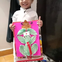 A proud student shows off his paper-folded Ganesha. This art project for Ganesh Chaturthi combines fine motor skills, following sequences, and cultural learning in a single, joyful activity.