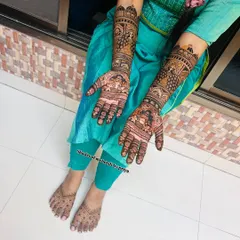 A top-down view of the engagement mehendi, showing the detailed work on both arms and feet. The designs feature traditional motifs like peacocks and elephants.