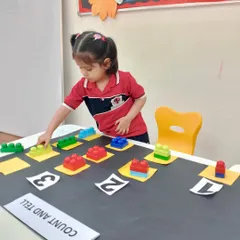 Learning to count is a colorful journey. This student is focused on arranging blocks to match the numbers, an exercise that strengthens her one-to-one correspondence skills and number recognition.