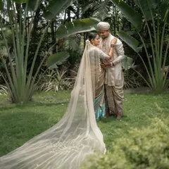 The bride's veil tells its own story. I love how the long, flowing fabric creates a sense of romance and drama, wrapping the couple in their own beautiful moment amidst a green, tranquil garden.