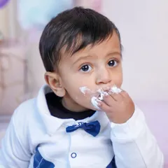 A close-up on the sweet taste of victory. This shot focuses on the baby's expression as he enjoys his first birthday cake.