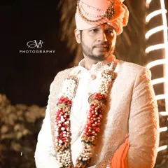 A classic groom portrait captured at night. The warm backlighting and the groom's confident pose in his elegant sherwani and safa create a striking and timeless image.