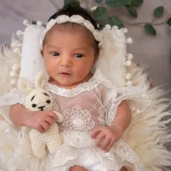 A close-up of the awake baby from the panda theme. She is holding a tiny crocheted bunny, looking right at the camera with her beautiful, curious eyes.