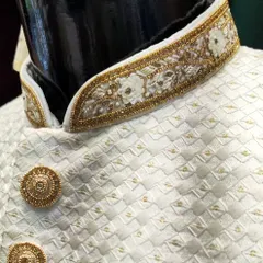 A detailed view of the hand-embroidered collar on a white sherwani. The combination of delicate floral threadwork and beadwork showcases the timeless elegance of my craft.