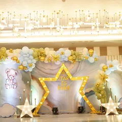 For this naming ceremony, the theme was 'A Star is Born'. The main backdrop featured a large light-up star, pastel blue and gold balloons, and adorable teddy bear cutouts for a celestial, dreamy feel.